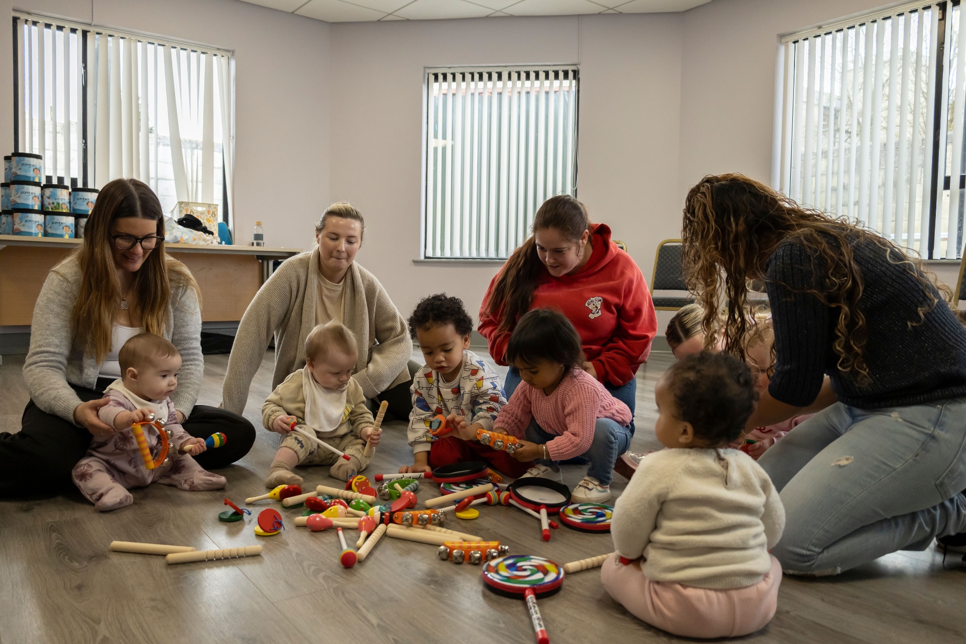 Mums and toddlers exploring colourful Zumbini instruments together